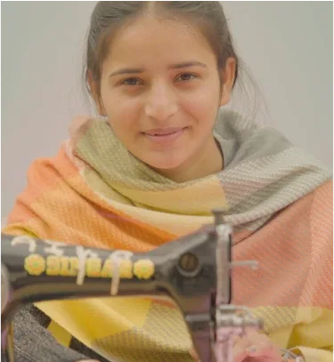 a young girl smiles while sewing on a sewing machine.