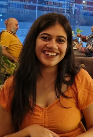 a woman sitting at a table smiling for the camera.